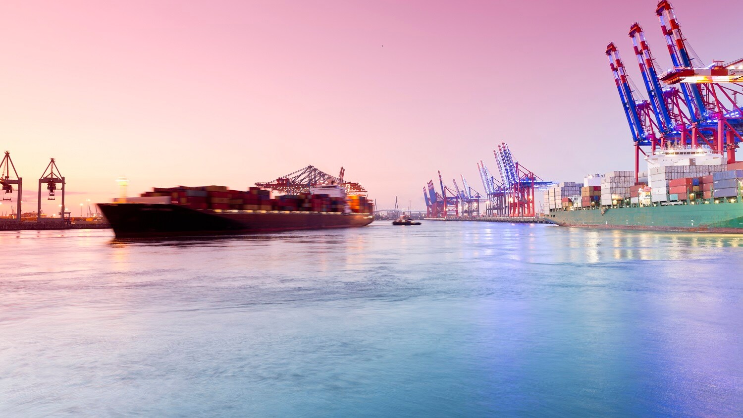 Image of a ship at port with cranes in the background
