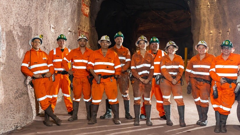 BHP men and women in tunnel entrance wearing orange PPE and smiling