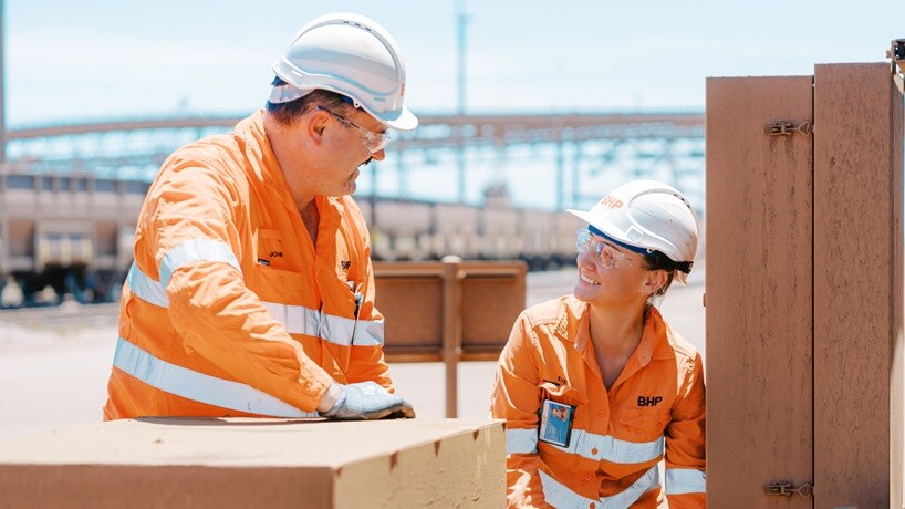 BHP uniformed man and woman talking and smiling at work in Port Hedland rail