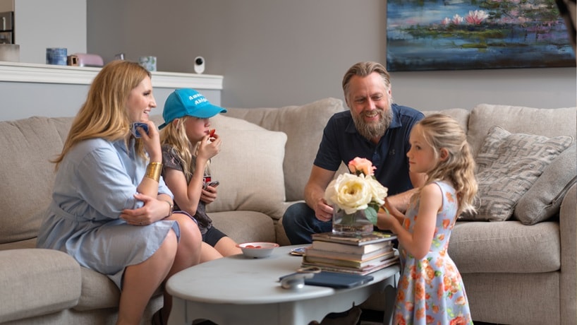 Family sitting in living room with two children smiling and flowers on coffee table