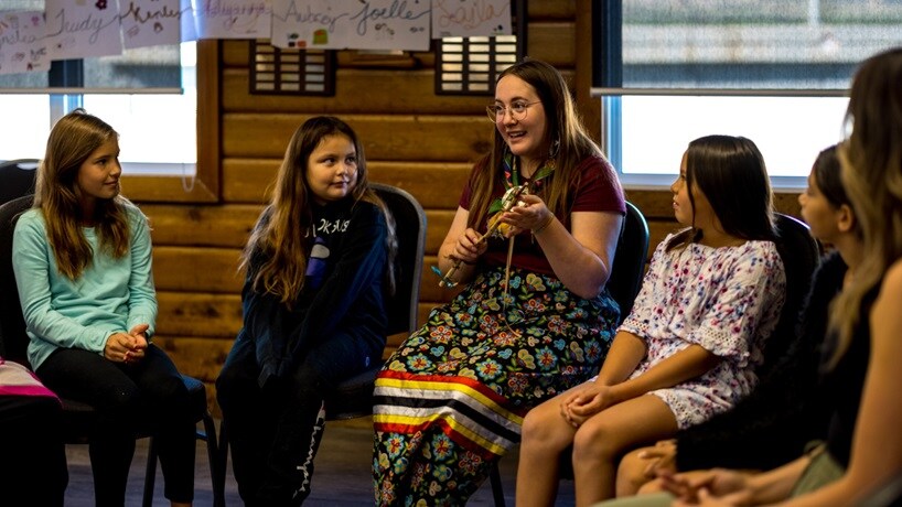 Woman sitting in a circle speaking and young people listening