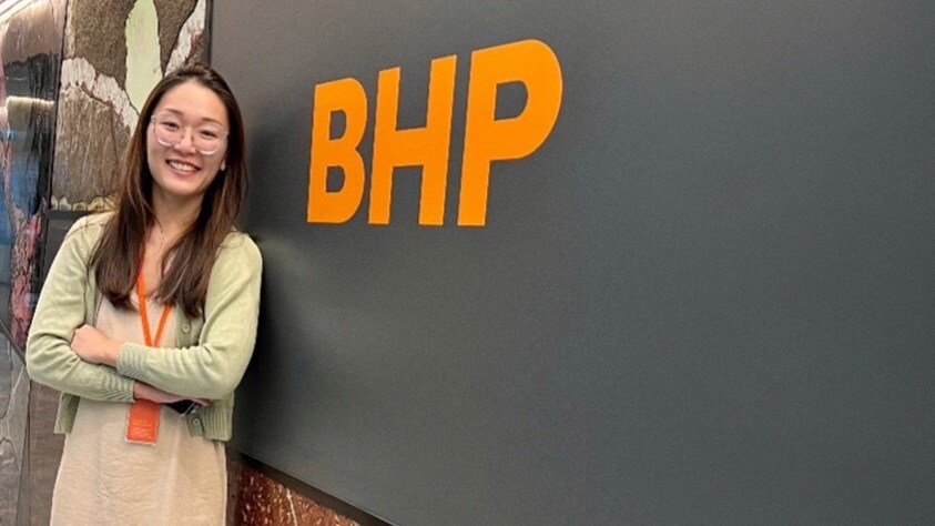 Nicole is shown smiling in front of BHP sign at Singapore office