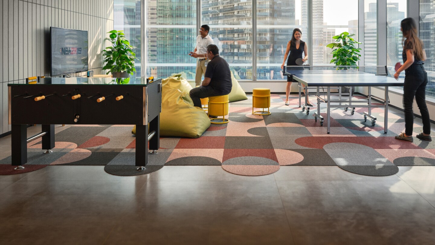 BHP team in relaxation space in Singapore office playing ping pong and watching tv with city in background
