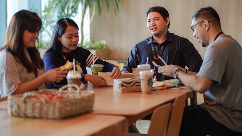 BHP Manila office people shown smiling and sitting sharing a meal