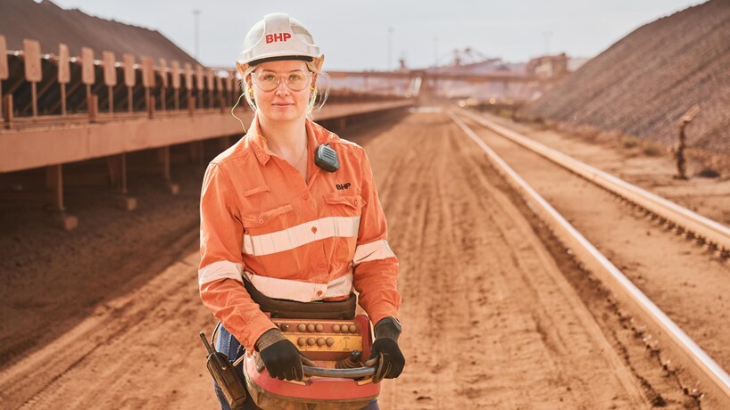 Woman standing on rail line in orange hi-vis
