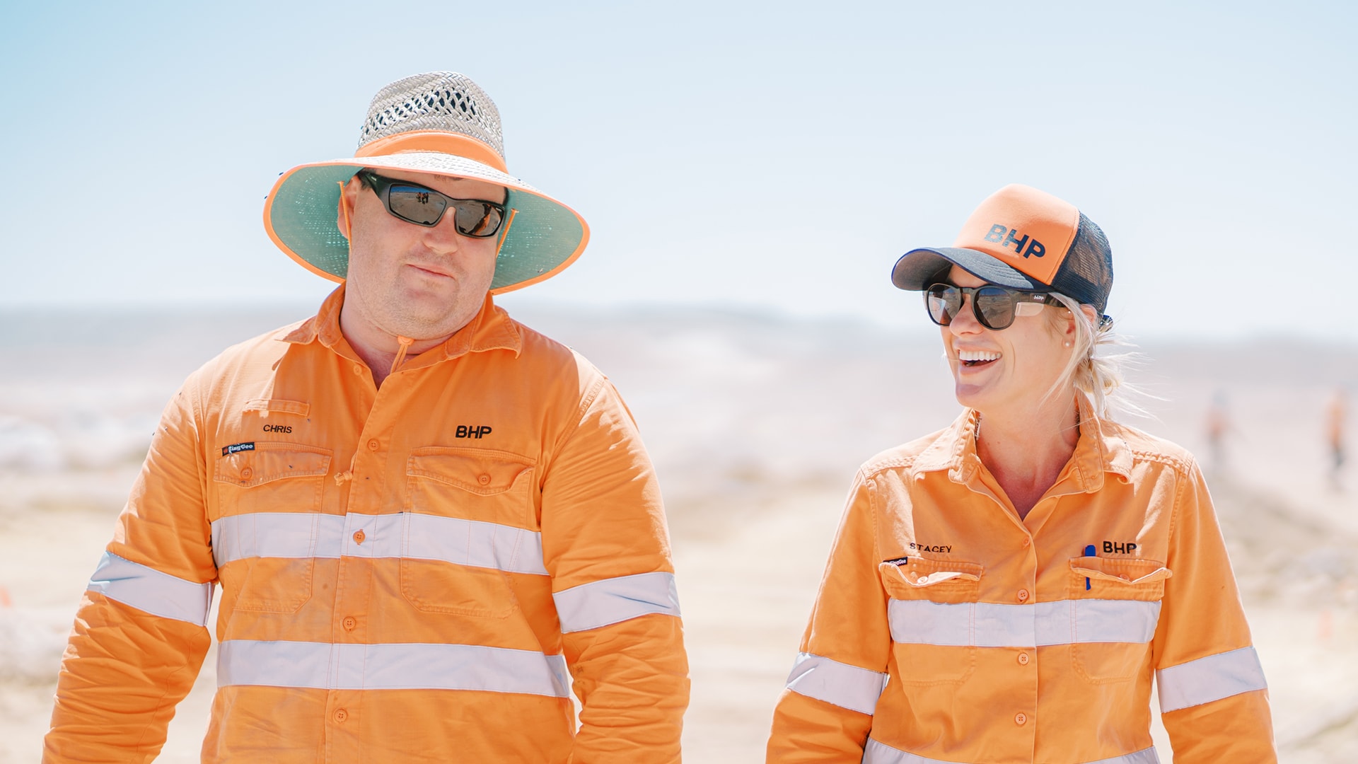 Man and woman walking wearing BHP orange working outside