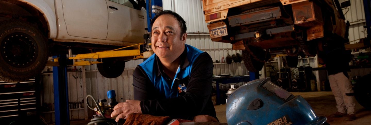 MAN IN CAR WORKSHOP SMILING TO CAMERA