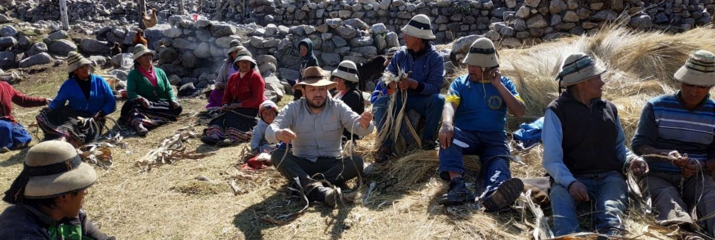 indigenous community in a circle looking at a man weave 