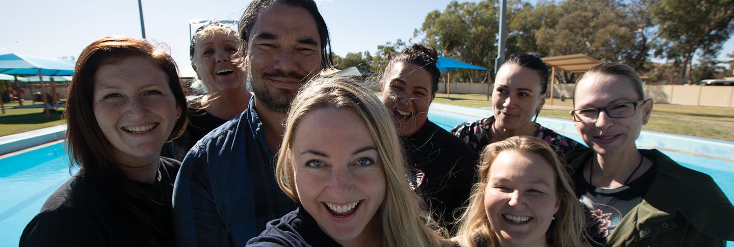 TEAM OF PEOPLE IN A GROUP PHOTO ALL SMILING TO CAMERA MIX MALE AND FEMALE