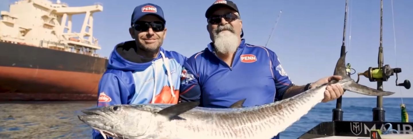 two mean holding a fish on a boat