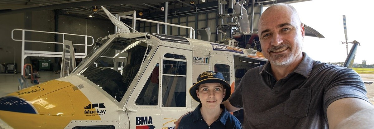 People smiling in front of helicopter