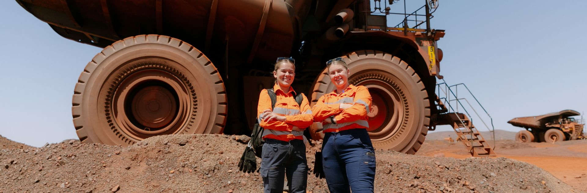two women at mining haul truck in PPE uniforms