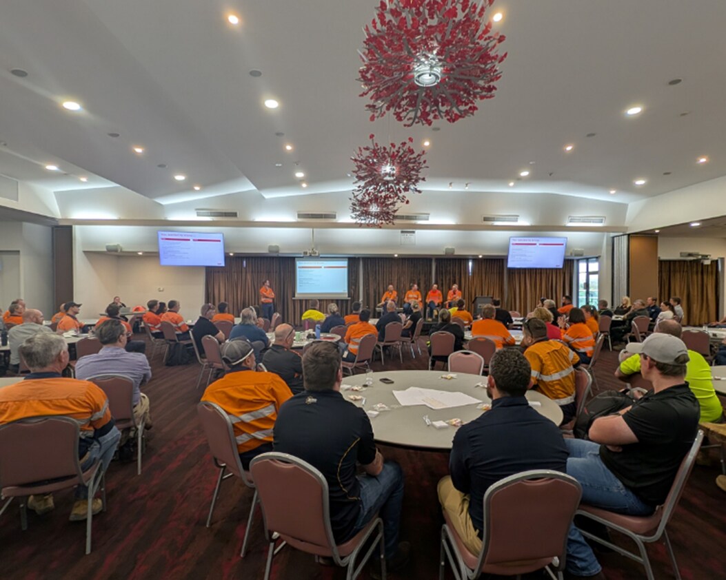 Large venue room with people sitting at tables for conference