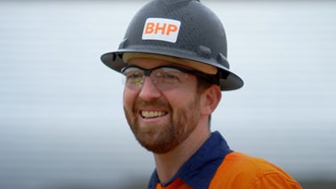 Man shown smiling, wearing a BHP branded shirt and black hard hat