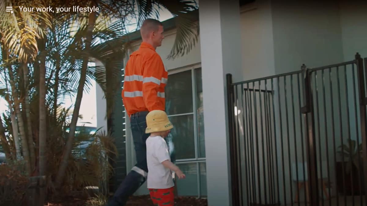 Man in BHP orange shirt walking child into childcare centre