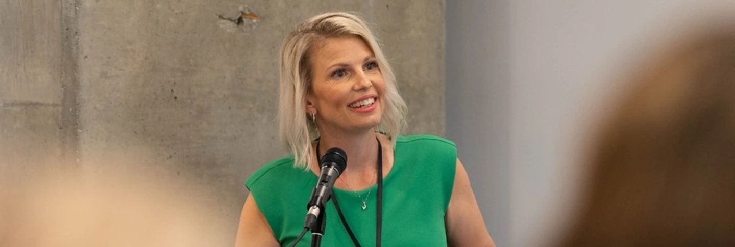 woman speaking at a conference smiling 