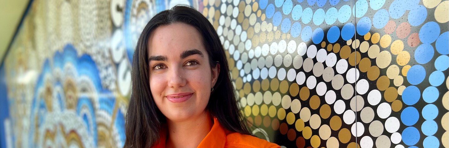 woman in mining uniform smiling to camera Indigenous artwork background
