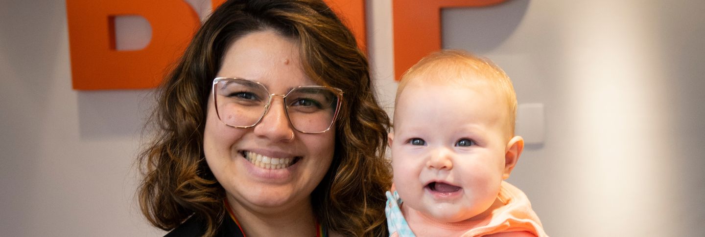 woman smiling to camera with baby daughter background BHP sign 