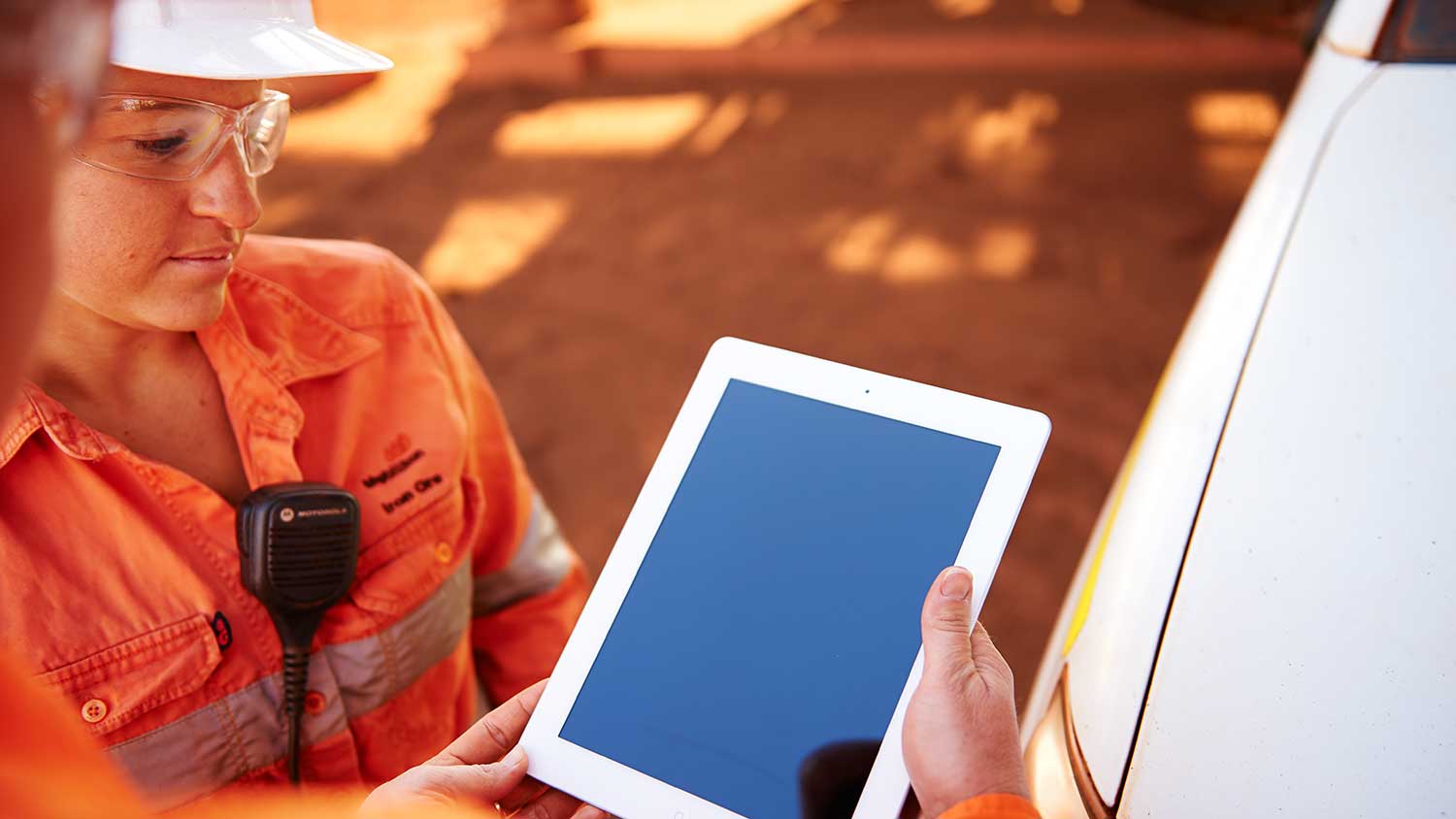 Two employees looking at tablet on site