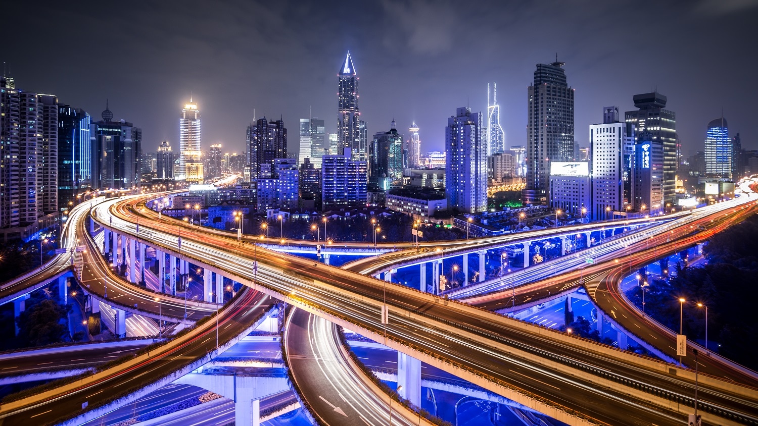 Freeway lit up against the backdrop of city buildings at night