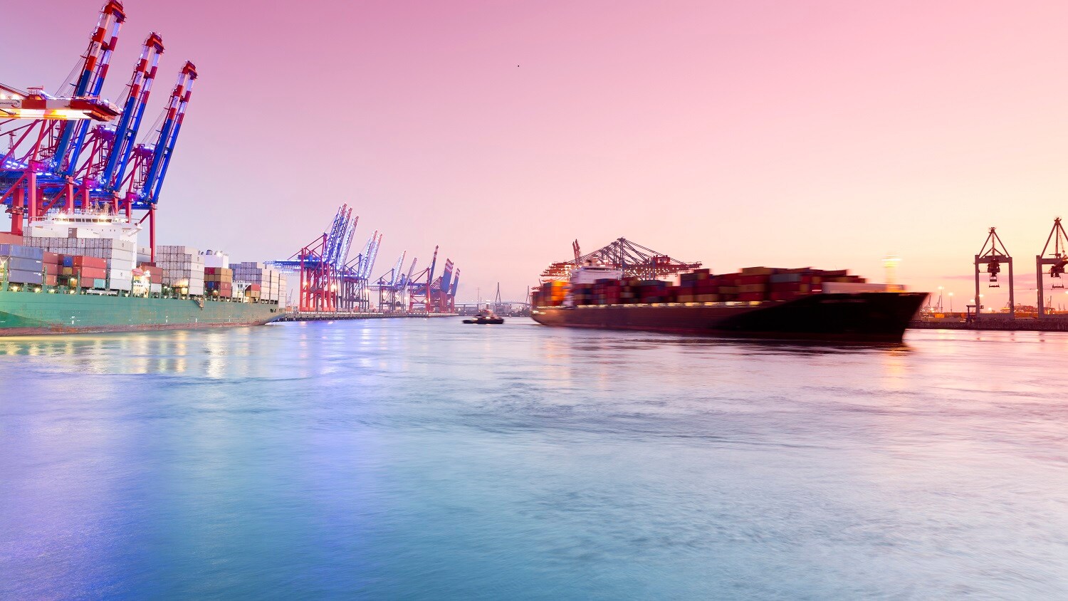 Image of a ship at port with cranes in the background