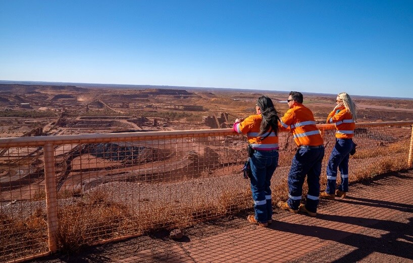 3 workers leaning on a fence in the desert