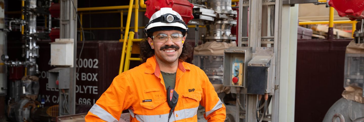man with moustache in BHP mining uniform standing facing camera smiling