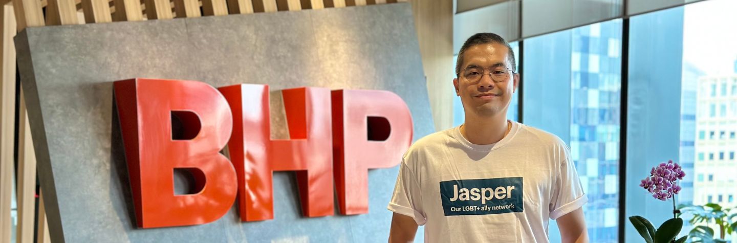 man standing beside the BHP sign with a jasper t-shirt on