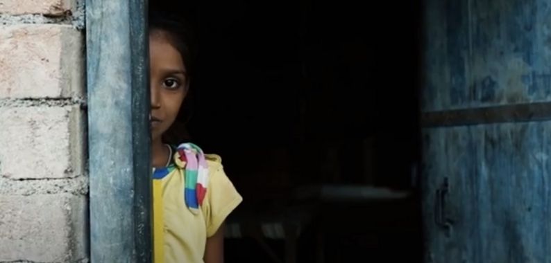 A young woman peeks out of a door