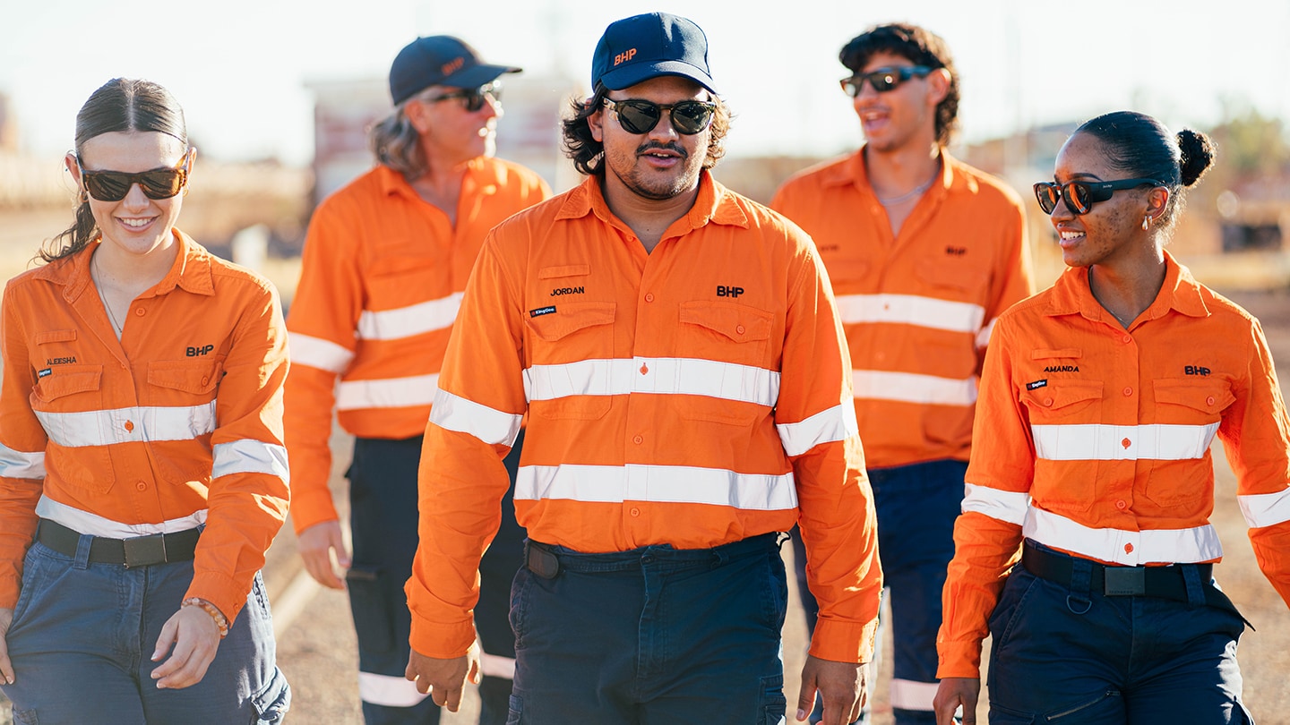 People walking in BHP uniforms on mine site showing diversity 