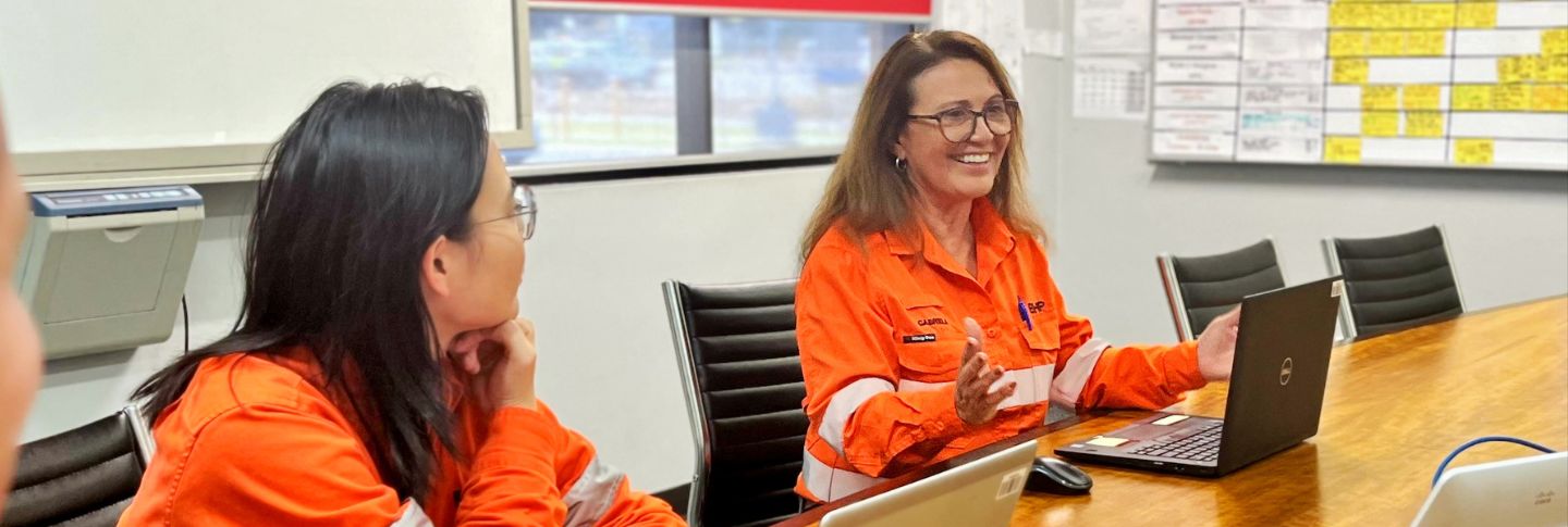 woman in mining office smiling at her laptop