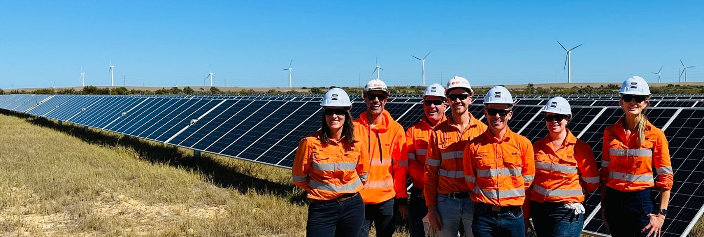 mining team in uniform standing next to a solar farm